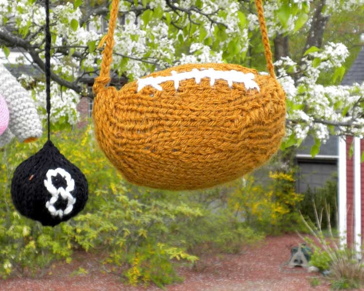 A knitted football and 8-ball hanging from blossoming branches