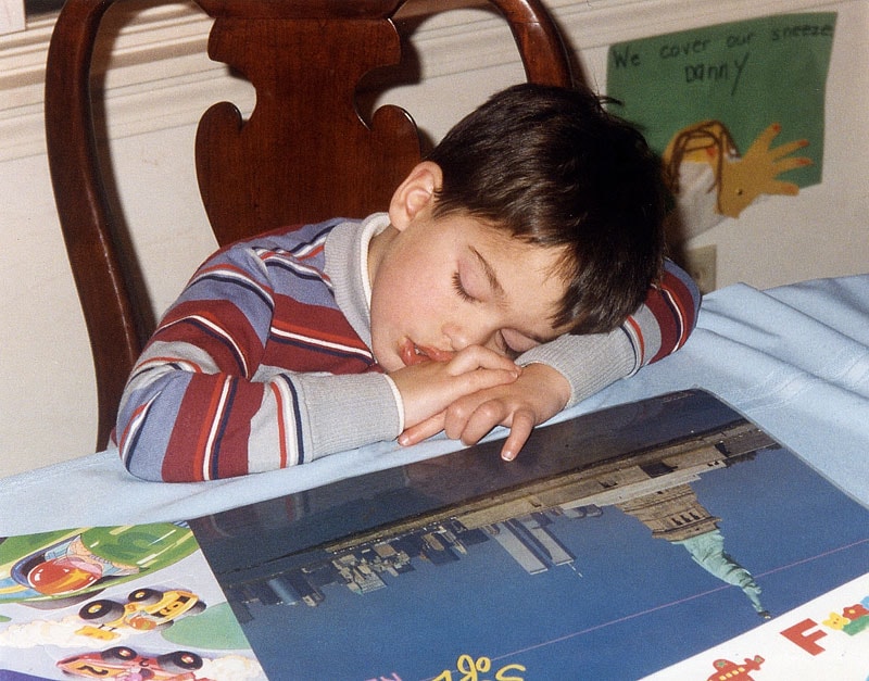 Young Tommy asleep at a desk with a New York City book