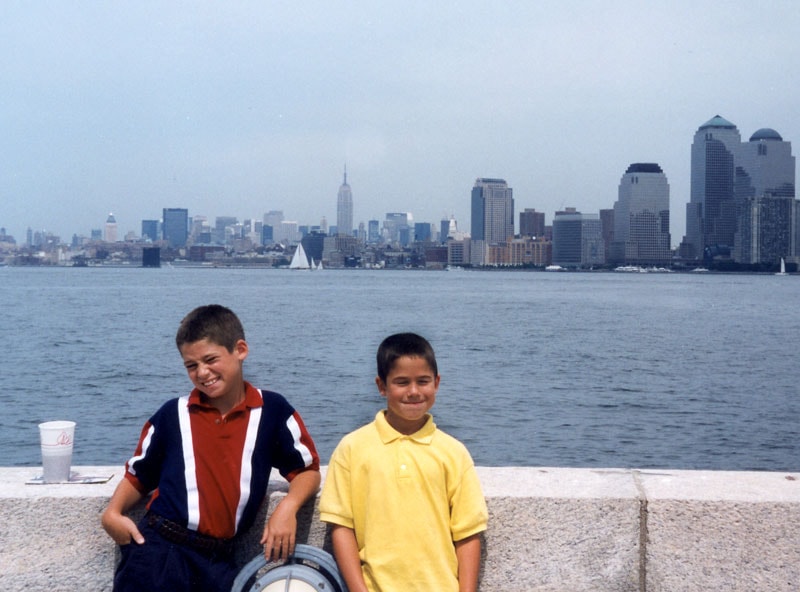 Tommy and Dan at Ellis Island with the Manhattan skyline behind them, 1997