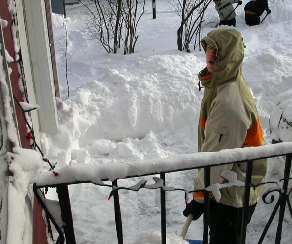 Person on a snowy porch surrounded by deep snow after a major storm