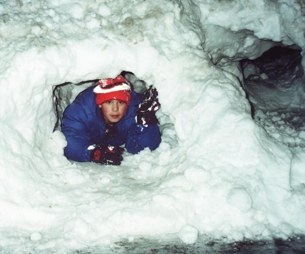 Tommy crawling through a tunnel dug in deep snow banks