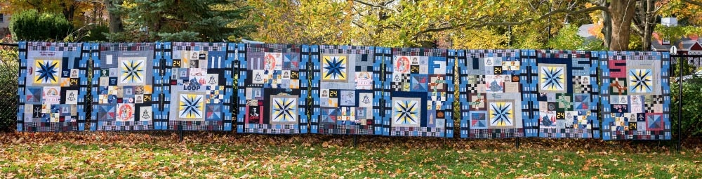 All 20 Tommy memory quilts displayed on a fence